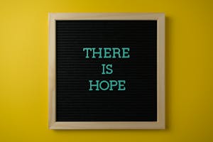 Letter board with 'THERE IS HOPE' message against a vibrant yellow backdrop.