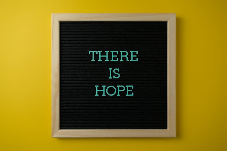 Letter board with 'THERE IS HOPE' message against a vibrant yellow backdrop.