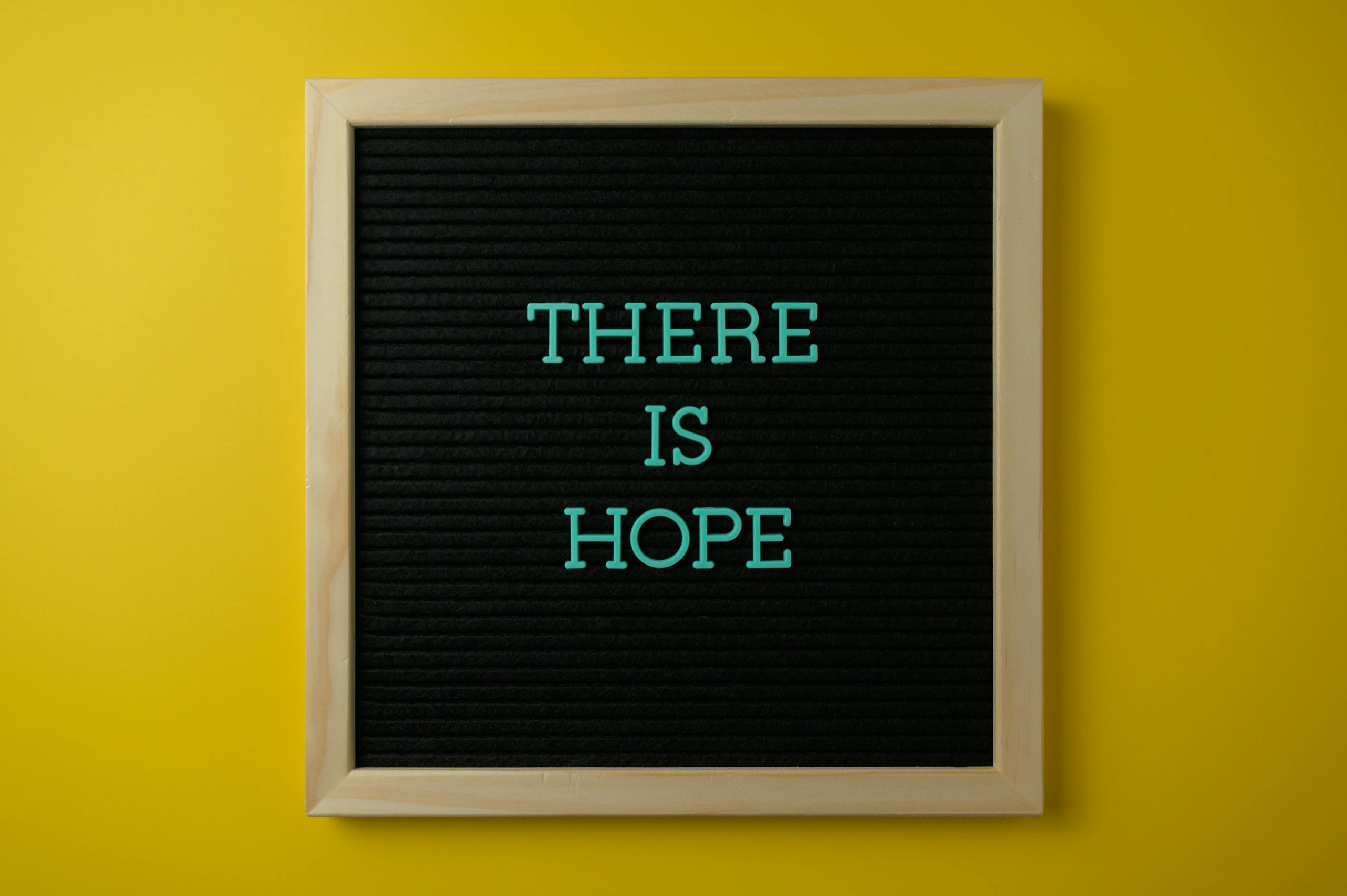 Letter board with 'THERE IS HOPE' message against a vibrant yellow backdrop.